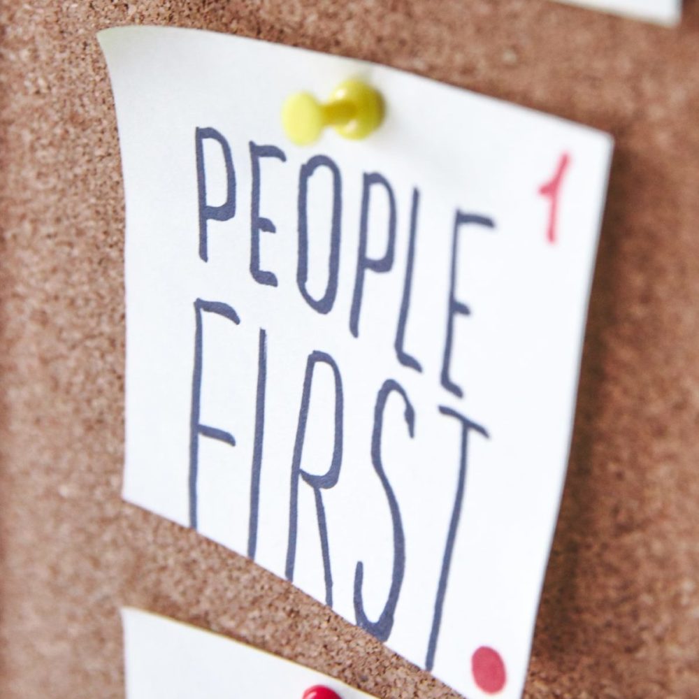 pinboard with a post-it that reads "people first"