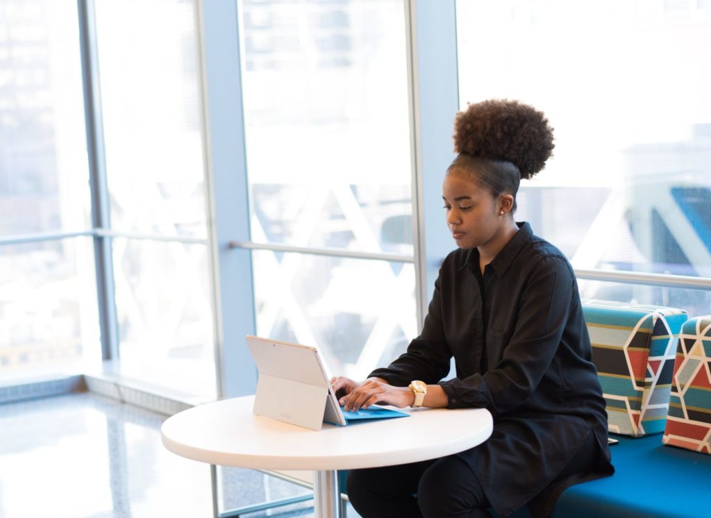 black woman sits at a table working in a light-filled room