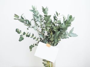 vase of eucalyptus branches with a blank 3x5 card note clipped in front