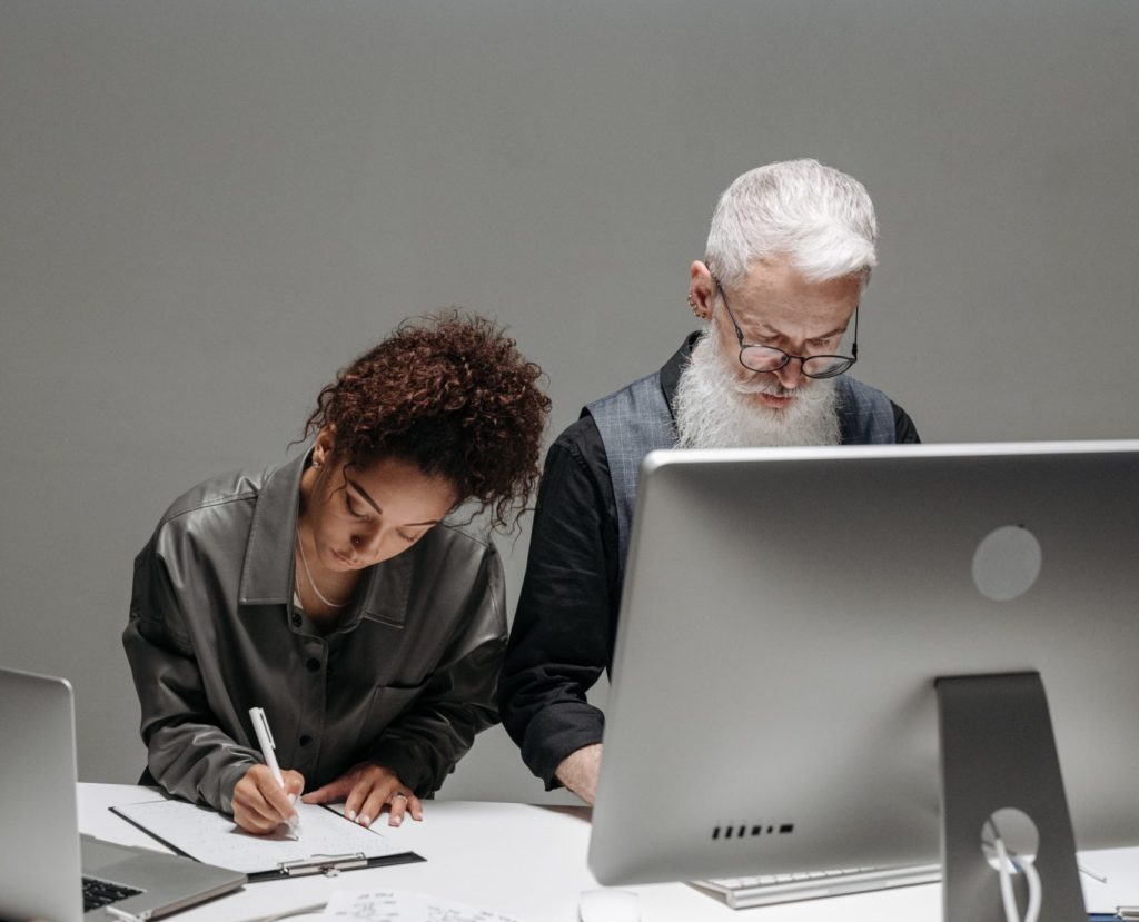 two people working, one at a desktop computer