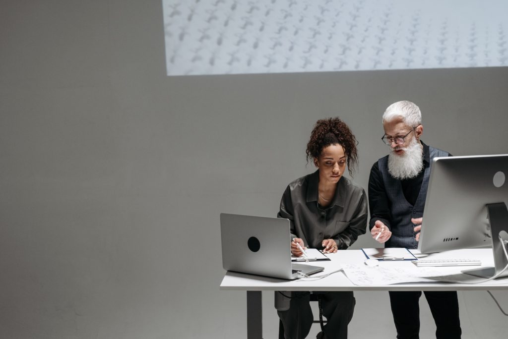 two people working at a desk with a projection behind them