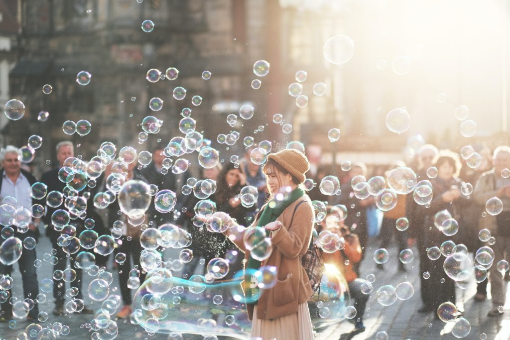 woman standing surrounded by bubbles with a group of people in the background